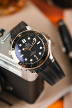 Load image into Gallery viewer, Light reflecting off the sapphire crystal of the Omega Seamaster Dive watch with wave detail on the dial