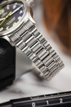 Load image into Gallery viewer, A close up view of the brushed links of the Omega Dynamic bracelet, the watch is leant against a black leather case with a watch tool in the foreground.